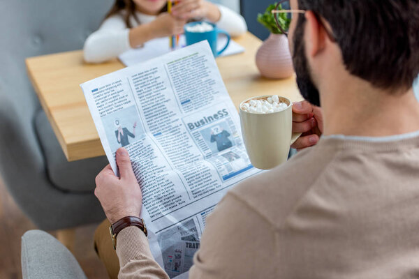 cropped image of father reading business newspaper while spending time with daughter in cafe 