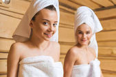 atraktivní mladé ženy s ručníky relxing v sauně a při pohledu na fotoaparát