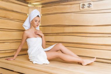 attractive young woman relaxing on bench at sauna clipart