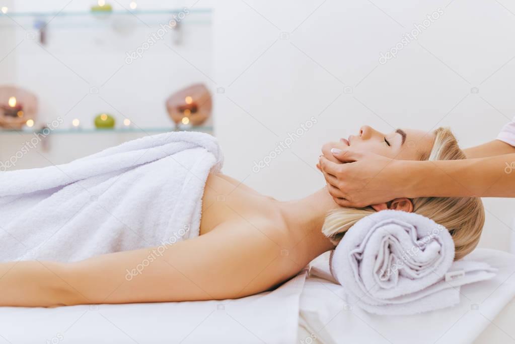 attractive young woman getting facial massage at spa salon
