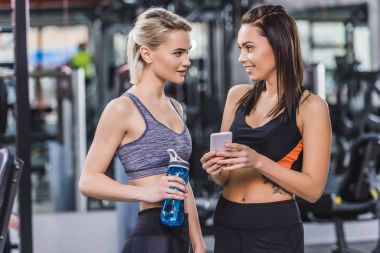 beautiful athletic women checking training results on smartphone at gym clipart