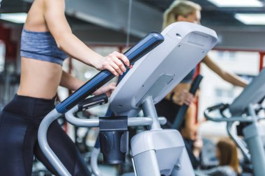 spor salonunda eliptik makinede çalışan sportif kadın görüntüsünü kırpılmış