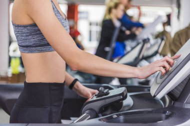 cropped shot of woman running on treadmill at gym clipart
