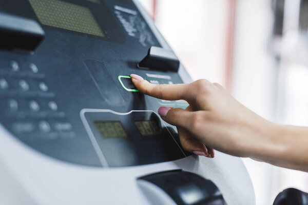 cropped shot of woman setting up elliptical machine