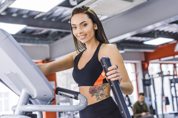 young sportive woman working out on elliptical machine at gym