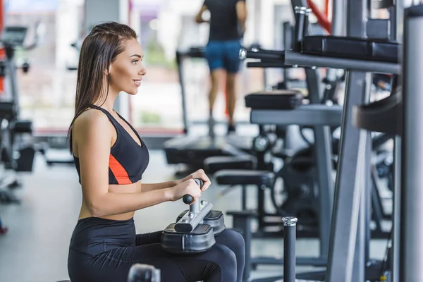 Ung Atletisk Kvinna Sitter Gymmet Maskin Och Tittar Bort — Stockfoto