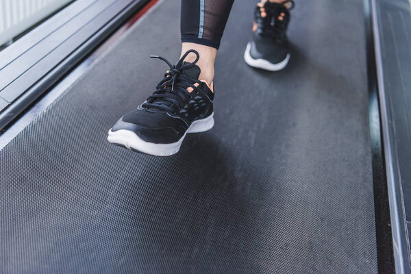 cropped shot of woman in modern sneakers running on treadmill