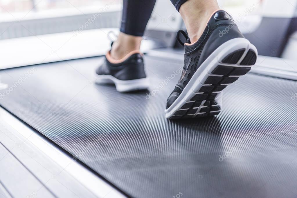 cropped shot of woman in jogging sneakers running on treadmill