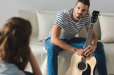 gitar ve evde kız arıyor kanepede oturan genç adam
