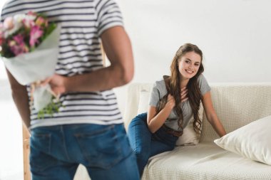 cropped shot of man hiding bouquet behind back to present it to girlfriend clipart