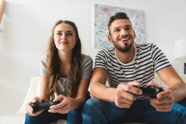 Gamepad ile evde oyun oynarken mutlu genç Çift