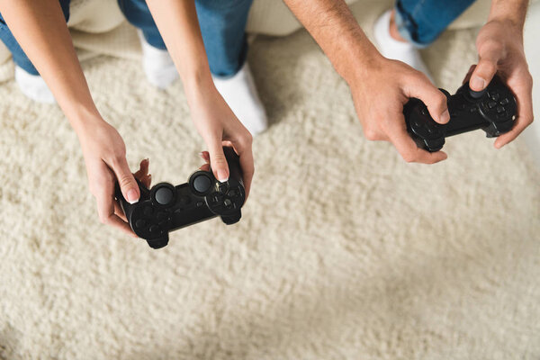 top view of couple playing computer games with gamepads