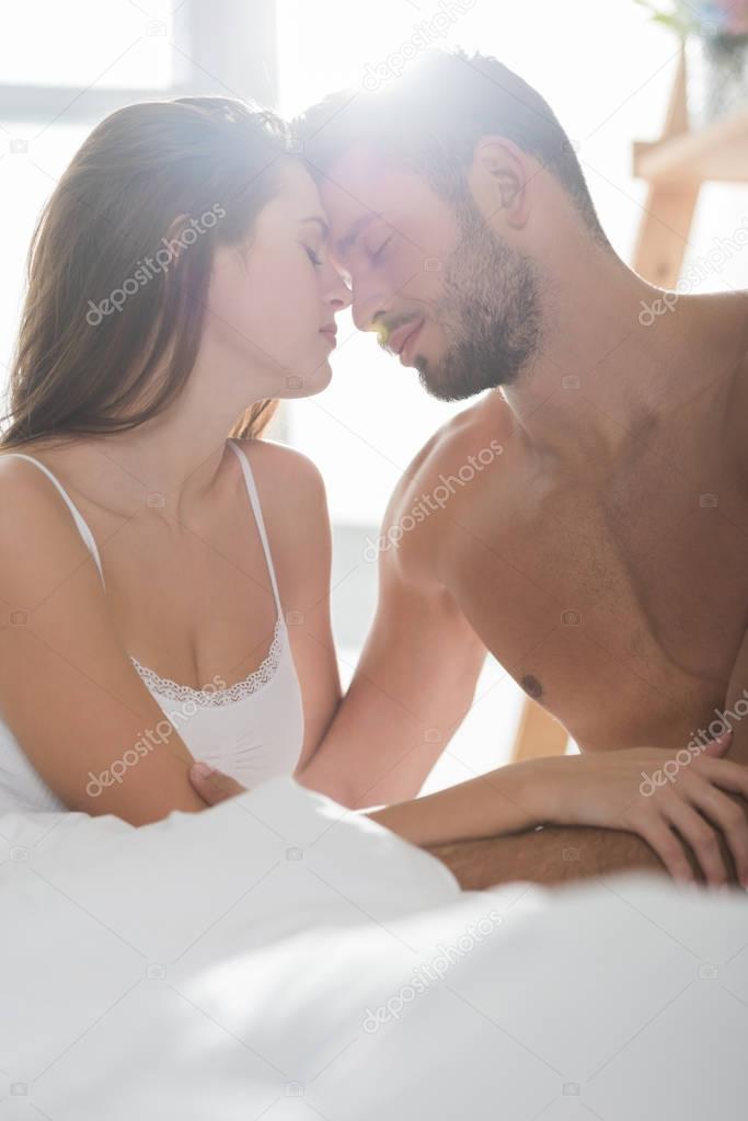 beautiful young couple in underwear cuddling in bed in morning