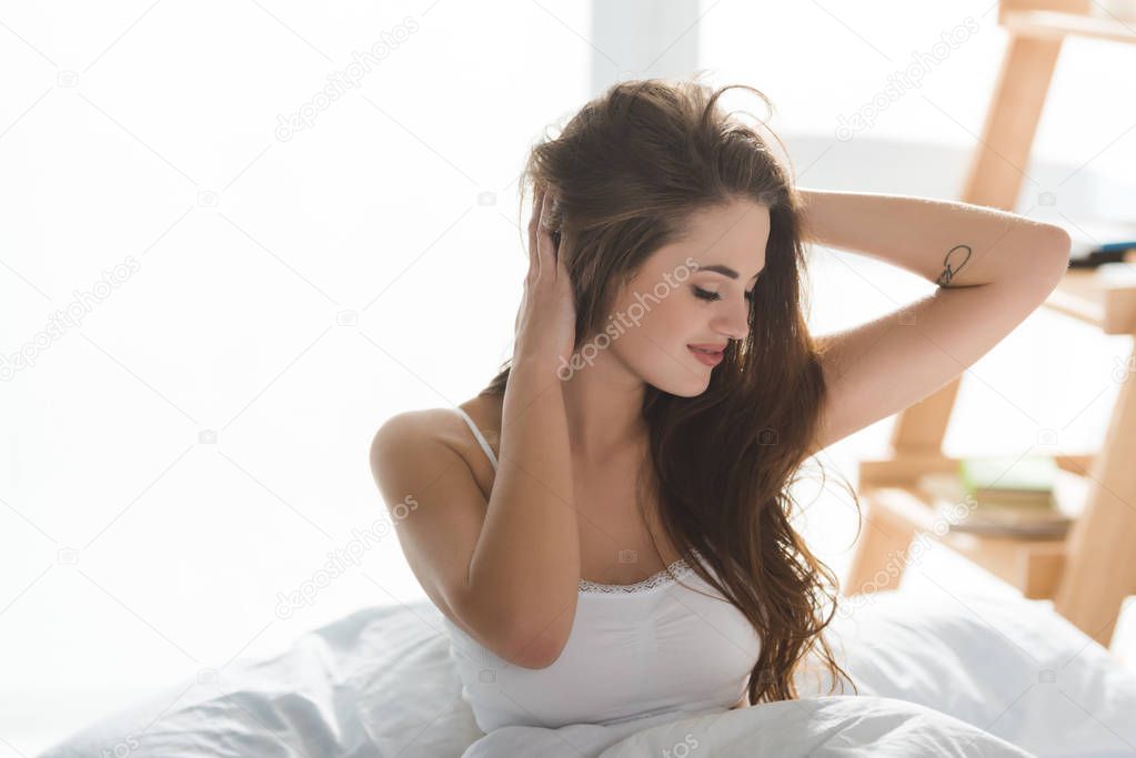 happy young woman relaxing in bed in morning