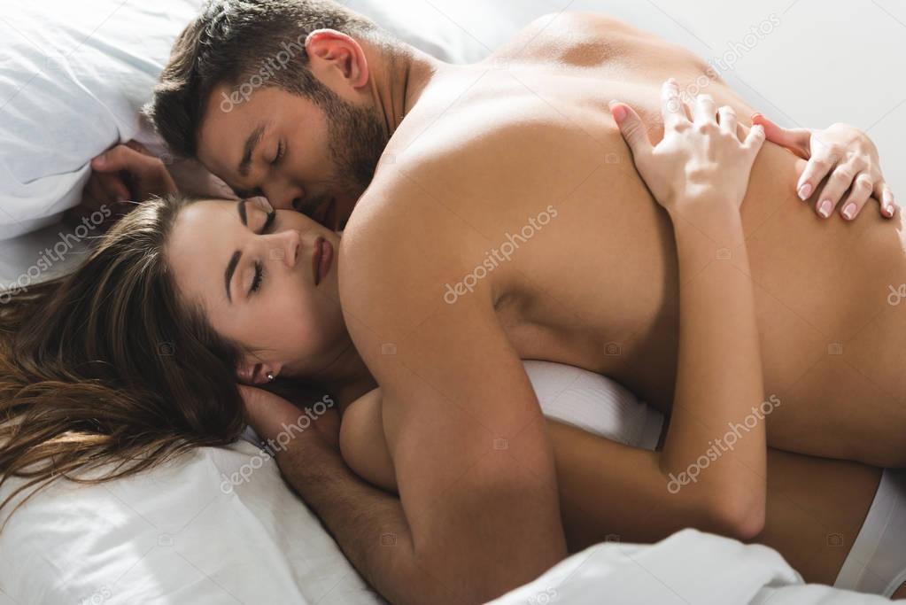 beautiful young couple cuddling in bed in morning