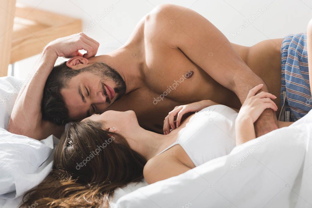 happy young couple cuddling in bed in sunny morning