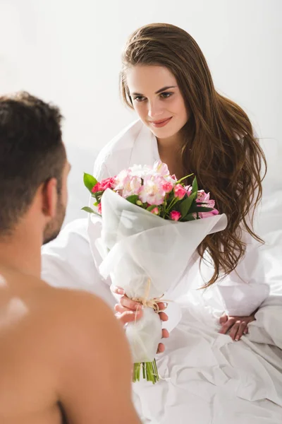朝のベッドでガール フレンドに美しい花束を提示する男 — ストック写真