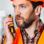 Trabajador en casco usando walkie talkie