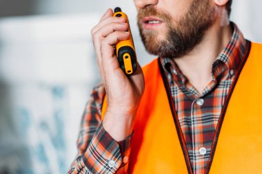 cropped view of worker in safety vest using walkie talkie clipart