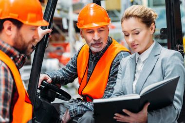 two workers and inspector using forklift machine in storehouse clipart