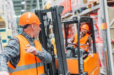 erkek işçi ve iş arkadaşı depo içinde forklift makine ile çalışma