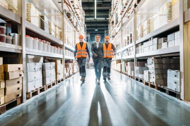 workers and inspector going along the corridor in storehouse clipart