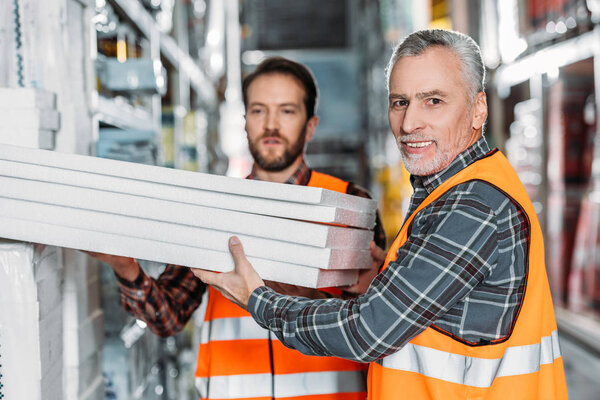 two male workers holding styrofoam in shipping stock