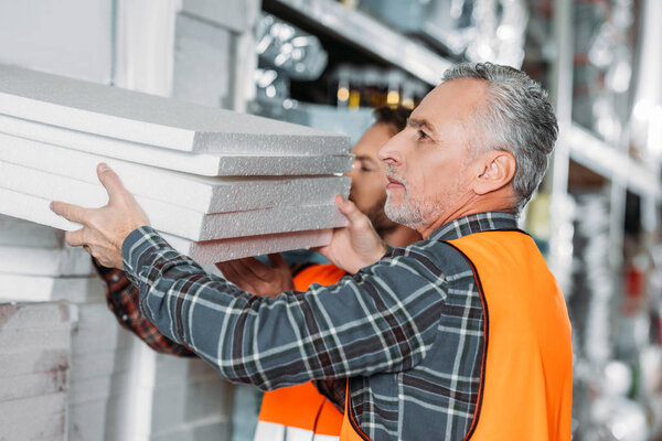 two male workers holding styrofoam in shipping stock