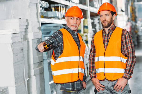 two male workers holding walkie talkie in storehouse