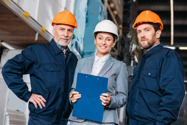 male workers and female inspector in helmets in shipping stock