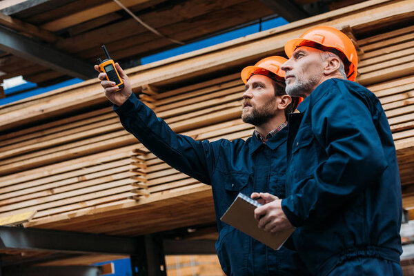 builders in helmets pointing with walkie talkie on construction