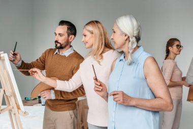 Olgun sanatçılar birlikte resim sanat sınıfında yan görünüm