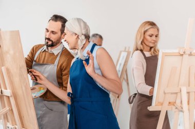 Yetişkin öğrenciler sanat dersinde Sephalar üzerinde boyama önlükleri 