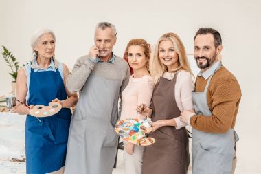 önlük sanat dersi kameraya gülümseyen kıdemli ve olgun sanatçıları