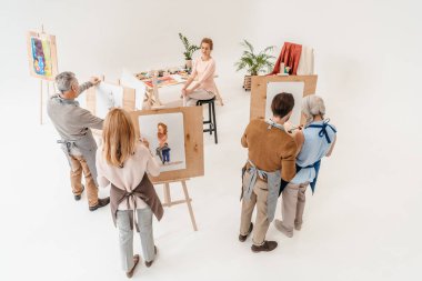 high angle view of senior people painting on easels during art class clipart