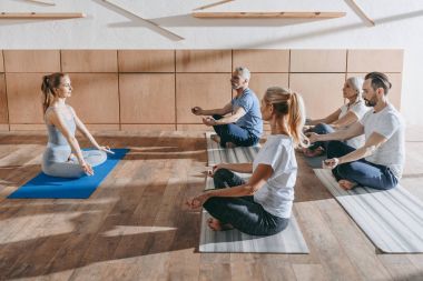 Grup pratik yoga hocası Studio paspaslar üzerinde lotus poz ile üst düzey insan
