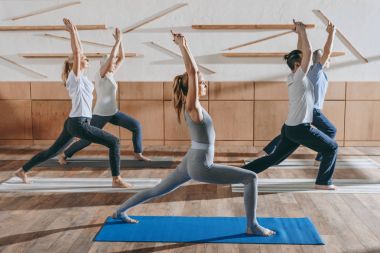 Grup pratik yoga hocası Studio paspaslar üzerinde savaşçı poz ile üst düzey insan