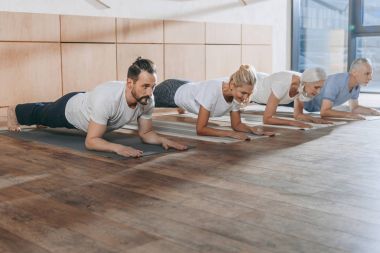 bir grup insan tahta üzerinde yoga paspaslar Studio yapıyor