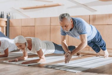 Grup üst düzey insan tahta üzerinde yoga paspaslar Studio yapıyor