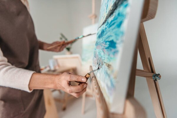 selective focus of artist with art tools drawing on easel