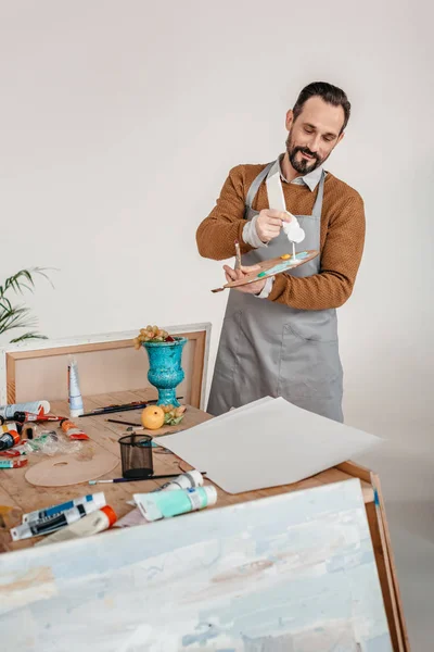 Palet Sanat Stüdyosu Içinde Tutarak Önlük Gülümseyen Olgun Erkek Sanatçı — Stok fotoğraf