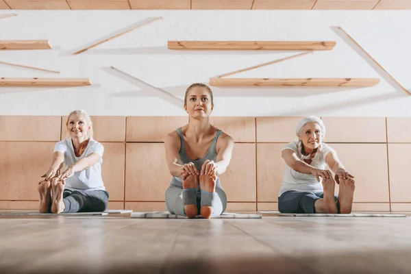 Grupo Mujeres Practicando Yoga Estirándose Sobre Esteras Estudio —  Fotos de Stock