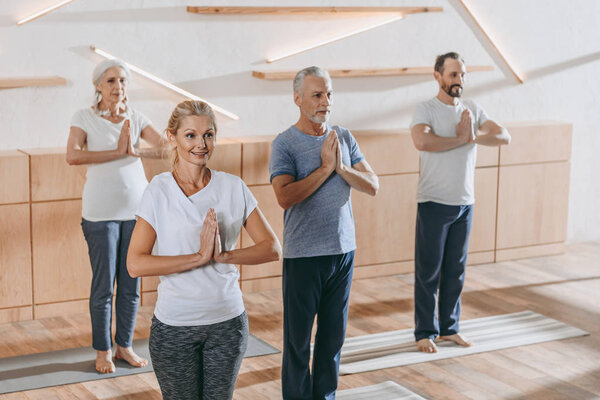 senior group of people with instructor practicing yoga at training class