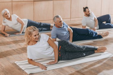 gülümseyen kıdemli insanlar Yoga eğitim eğitim sınıfında paspaslar