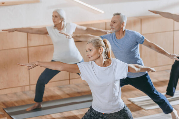 female instructor training with senior people in fitness studio