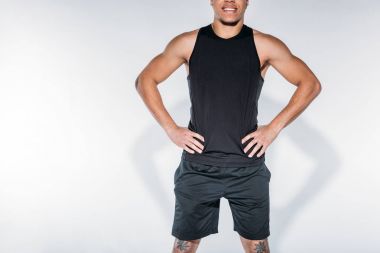 kırpılmış görüntü gülümseyen Afro-Amerikan sportif adam ayakta beyaz
