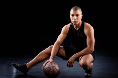 siyah topu ile otururken yakışıklı Afro-Amerikan basketbol oyuncusu