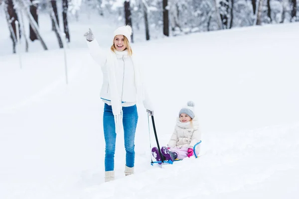 愉快的女儿和母亲雪橇一起在冬天公园 — 图库照片