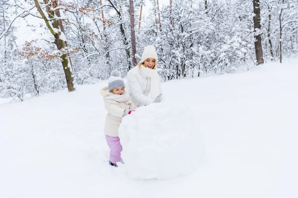 美丽的母亲和女儿在冬天公园做雪人 — 图库照片