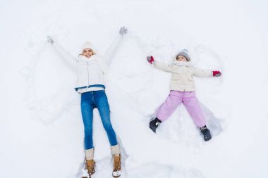 top view of happy mother and daughter making snow angels together  clipart